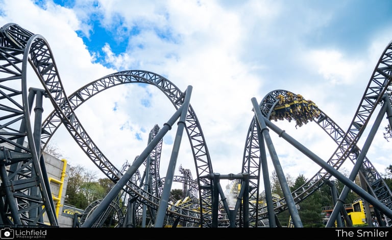 A Roller coaster in the shape of eyes and a smile with a cart on a loop to the Right
