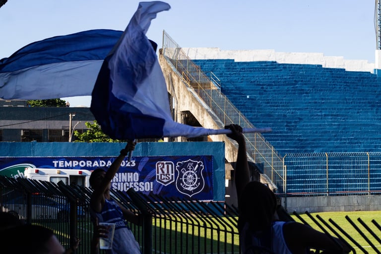 Torcida vibrando pelo seu time durante a partida, com foco na bandeira da torcida