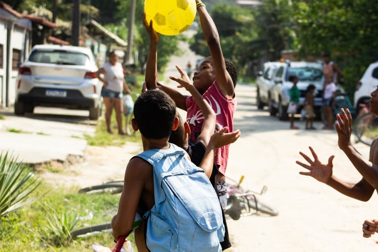 Crianças brincando, tentando pegar uma bola lançada ao ar