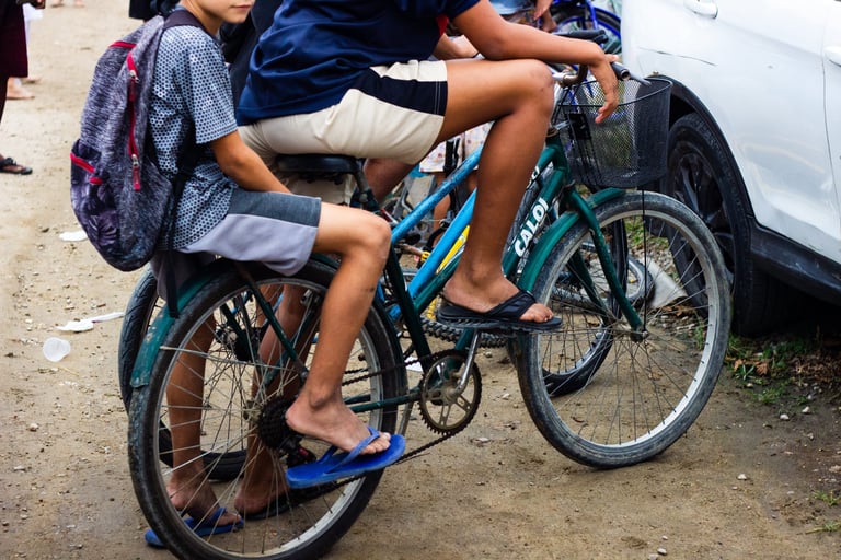Duas crianças sentadas numa bike, sem o rosto aparente