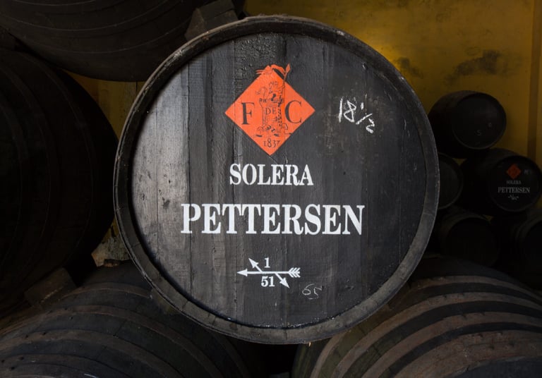 An image showcasing a sherry cask, adorned with the distinct logos of both Fernando de Castilla and Pettersen Brandy..