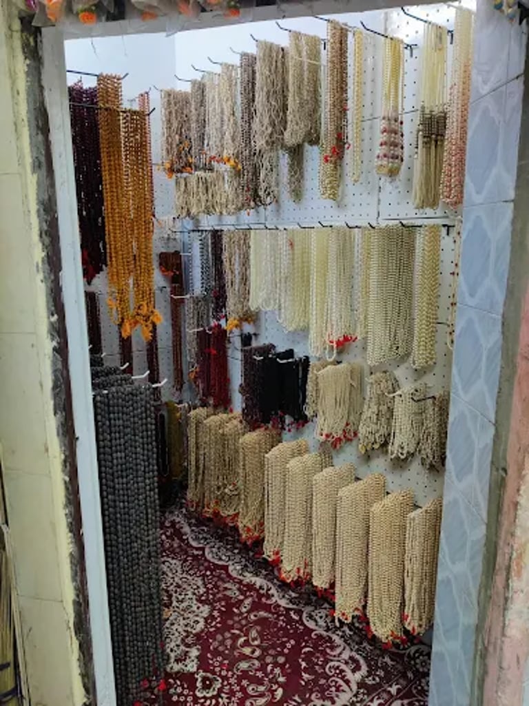 A variety of traditional Indian mala beads and prayer necklaces displayed on a wall in a shop.