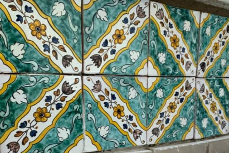 Hand-painted Mediterranean ceramic tiles featuring yellow floral patterns and green scrollwork.