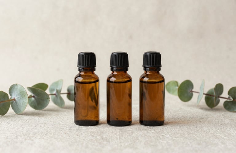 Minimalist photo of three glass bottles of essential oils arranged neatly on a textured soft cream linen cloth, natural eucalyptus green stems nearby.