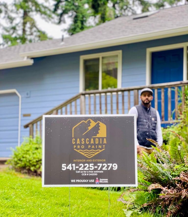 Cascadia Pro Paint yard sign in front of a blue residential house with a professional exterior painter.