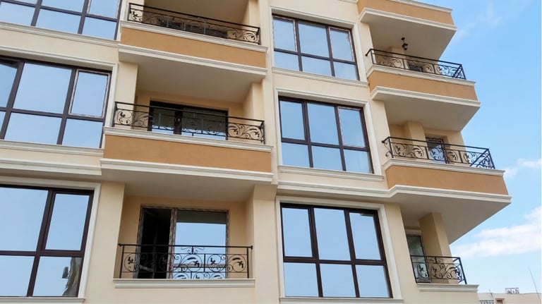 Modern apartment building exterior featuring balconies with ornate black wrought iron railings.