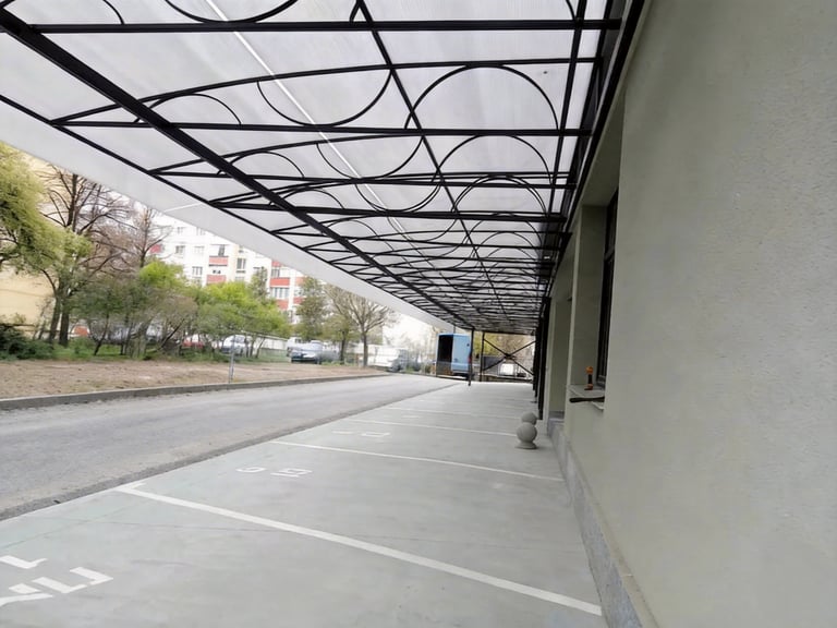 Modern polycarbonate awning with black metal frame covering a concrete parking area.