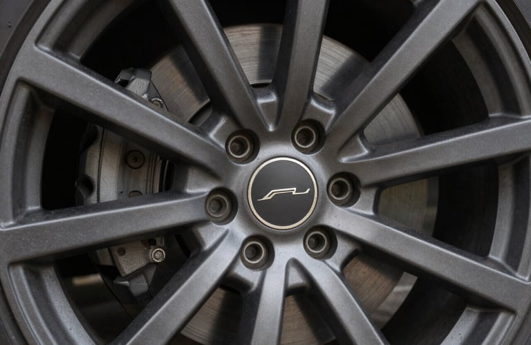 A detailed view of a multi-spoke alloy wheel with a matte charcoal finish, crisp focus on the brand emblem, professional North American studio lighting.