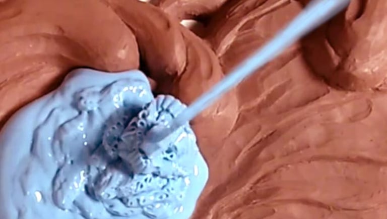 Pic of the custom mold making process. A stream of blue silicone poured over a clay sculpture