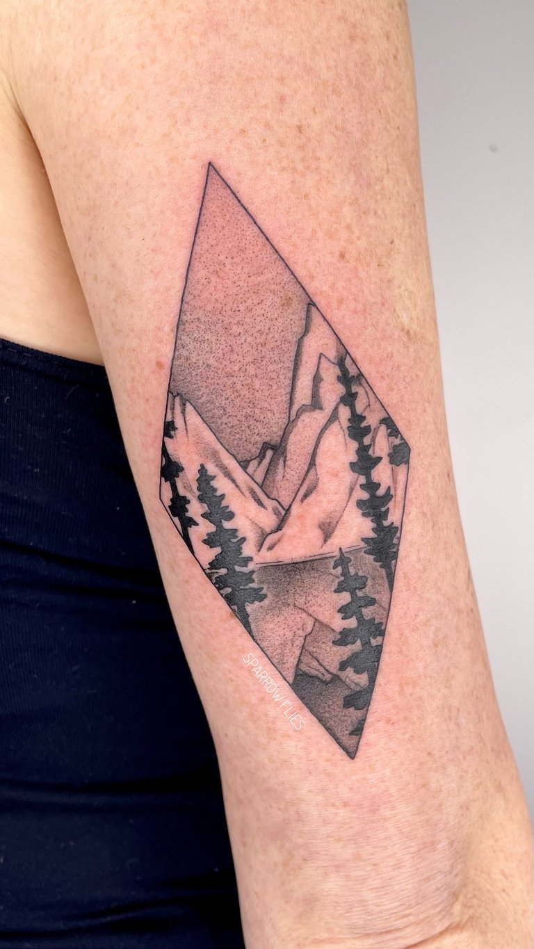 Whippshaded mountain landscape tattoo on the back of the upper arm