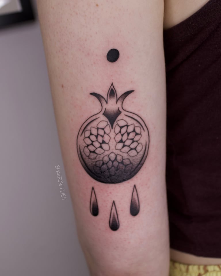 Blackwork pomegranate tattoo design with drops on the upper arm