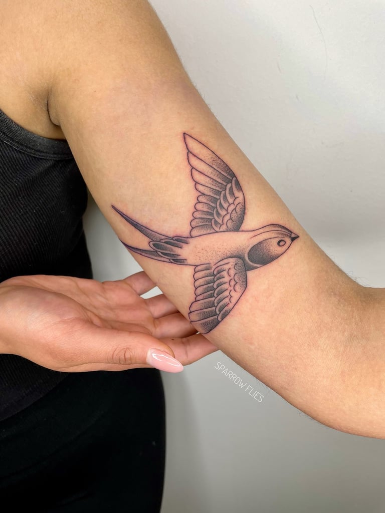 Illustrative swallow tattoo design on the upper arm