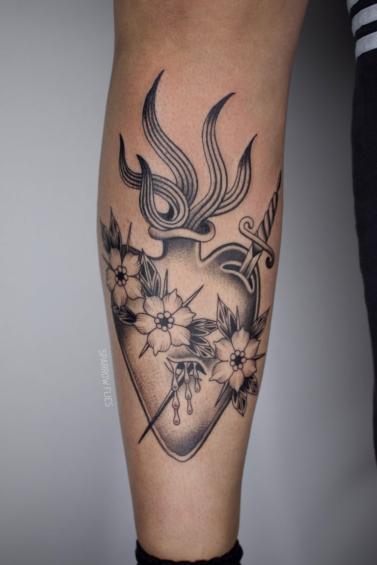 Sacred hear with flowers and dagger tattoo on the front of the leg