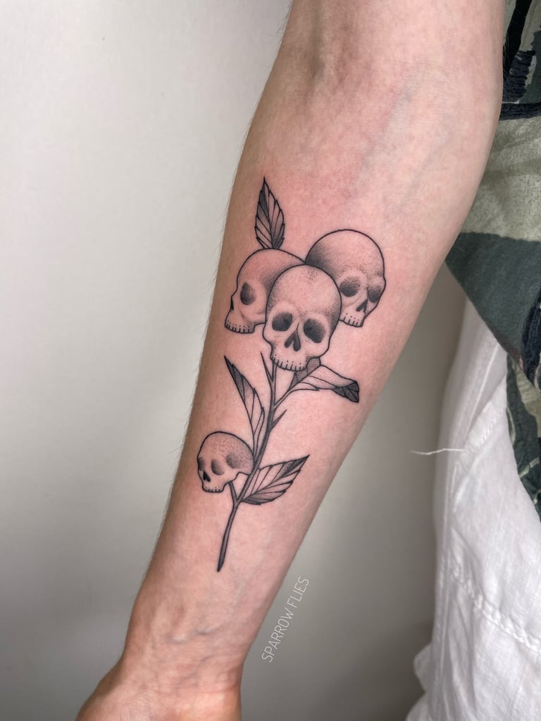 Fine-line skull with leaves tattoo design on forearm