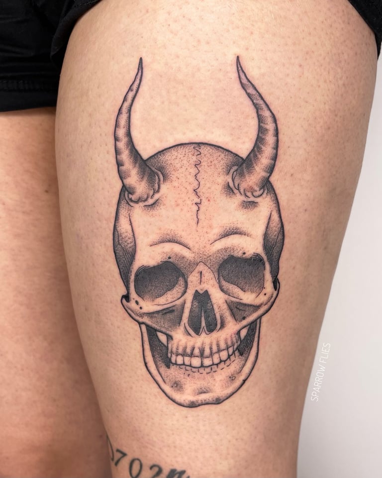 Illustrative skull with horns tattoo design on the thigh