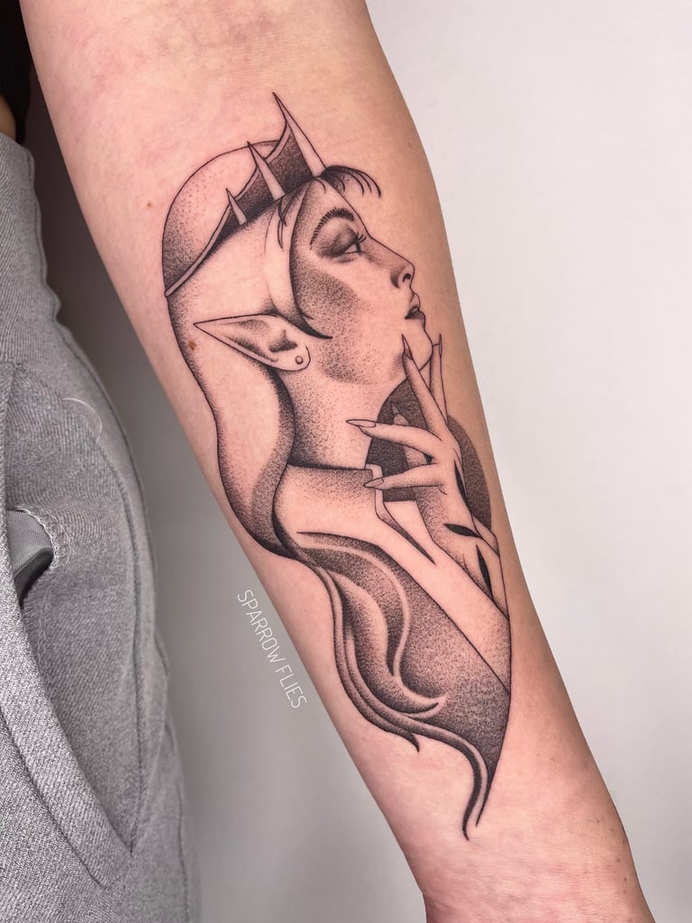 Black and grey tattoo of an elven woman with a crown and long flowing hair, done in dotwork style on the inner forearm