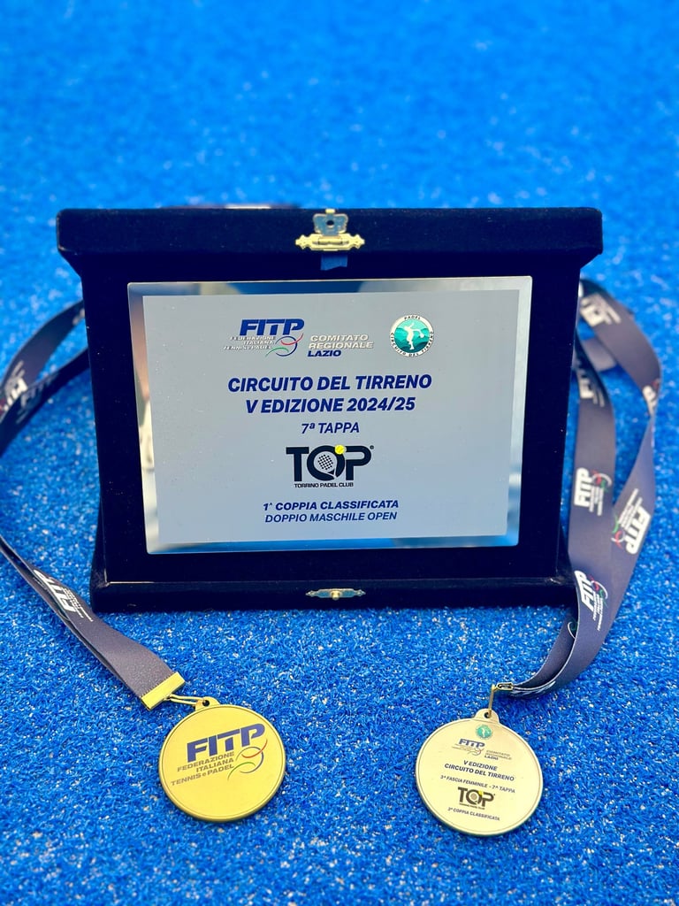 FITP Padel tournament award plaque and gold medals on a blue court for Circuito del Tirreno 2024/25.