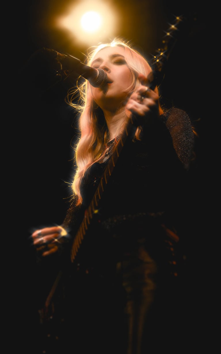 A singer playing guitart on stage with a spotlight shining down