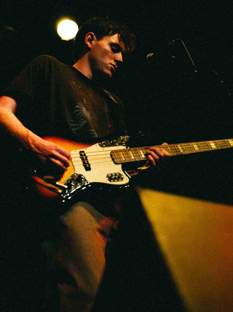 A guitartist playing on stage witha. stagelight shining down