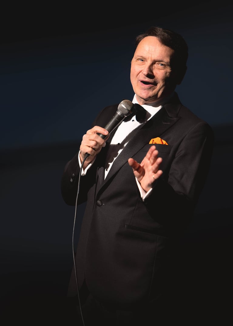 a singer in a suit and bow tie performing to the camera on stage