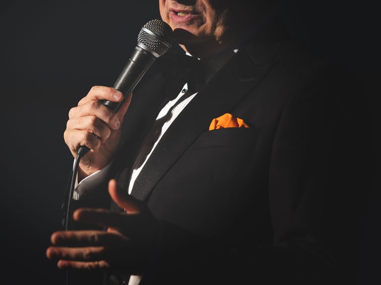 a close up photo of a singer in a suit and bow tie holding a microphone