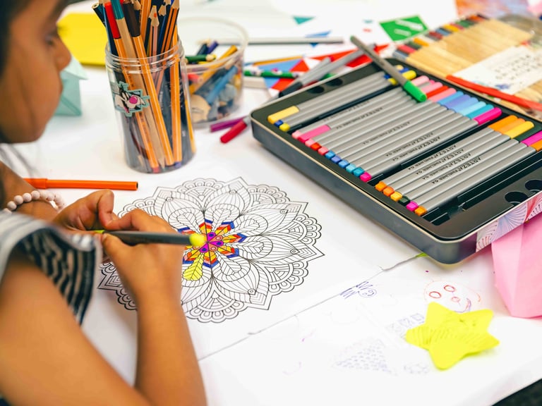 An over the shoulder photo of a girl colouring a mandala