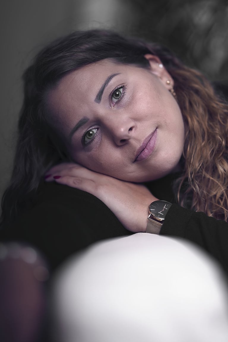 Portrait einer Frau mit dunkler Kleidung vor hellem Sofa und ruhigem Hintergrund