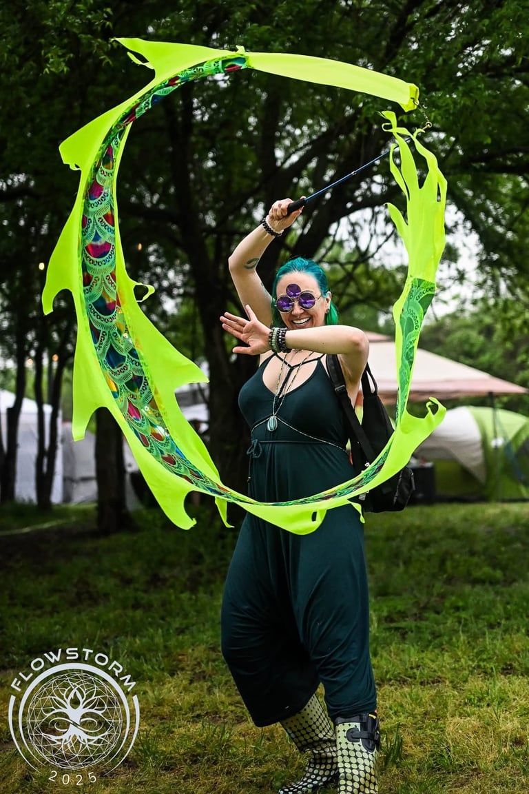 A woman with teal hair and third eye covering sunglasses spins a neon green dragon kite in a circle