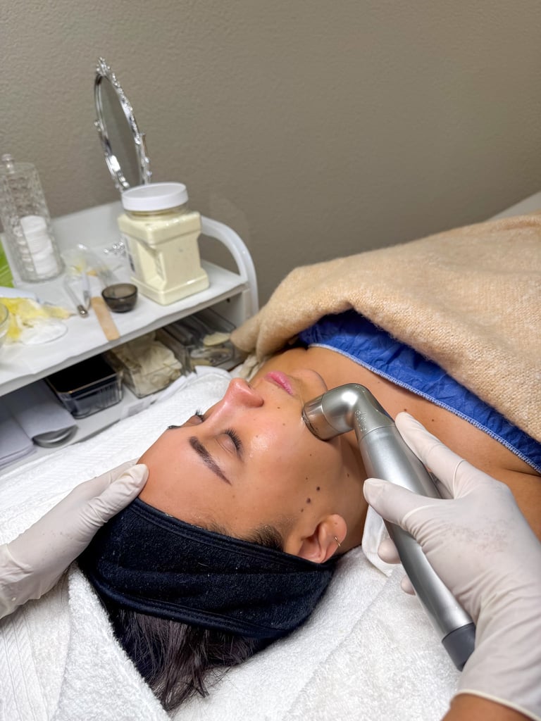 Esthetician performing a professional microdermabrasion facial treatment on a female client.