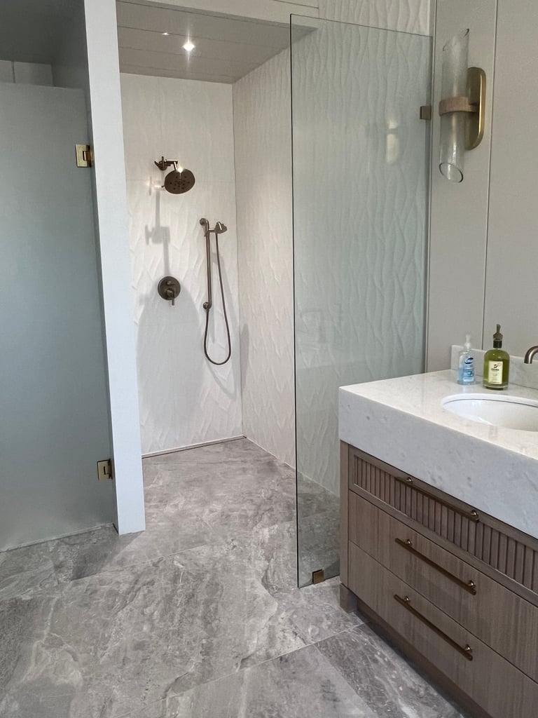 Modern bathroom featuring a walk-in glass shower, large format tile on floors and walls.