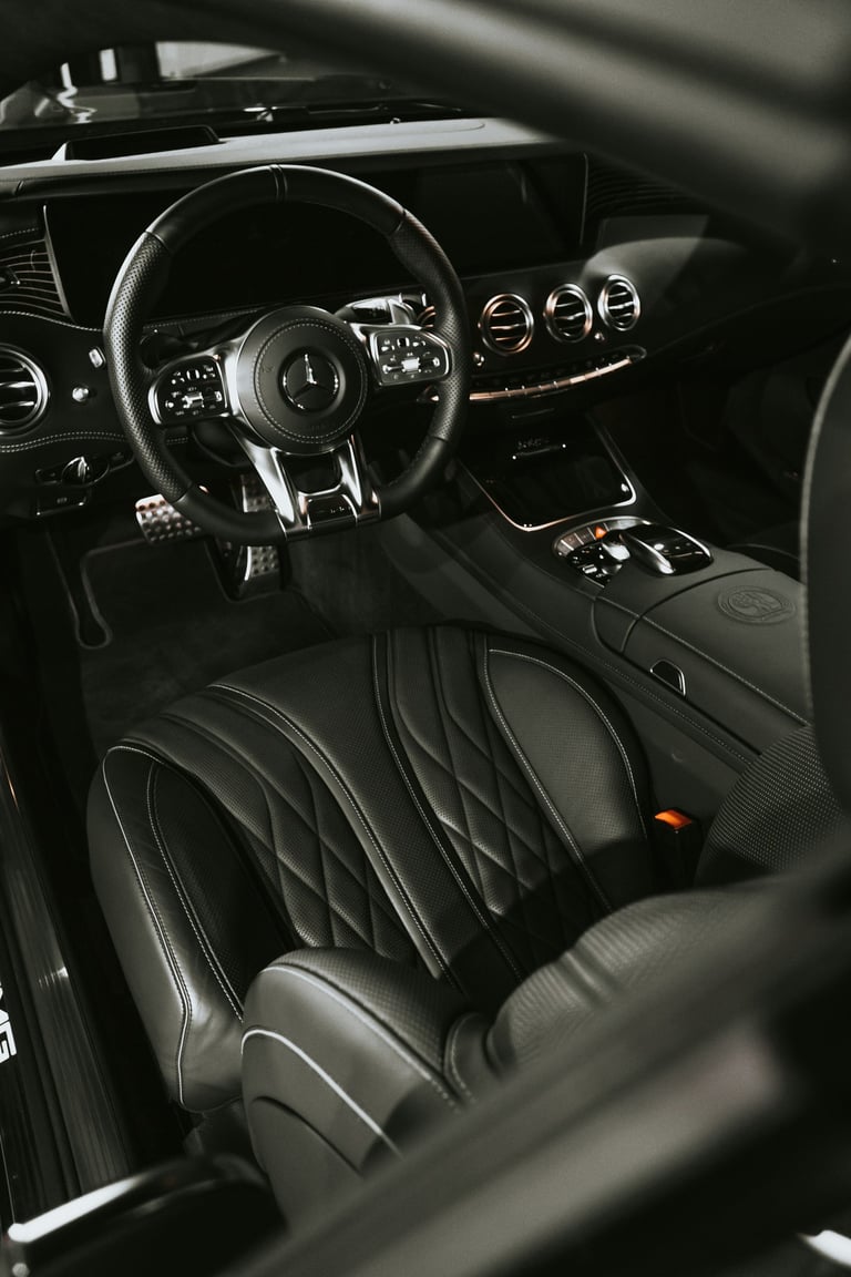 Luxury interior of a Mercedes-Benz AMG with black quilted leather seats and sport steering wheel.