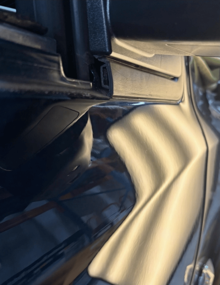 Close-up of a smooth car door panel reflecting light after a professional paintless dent repair service.