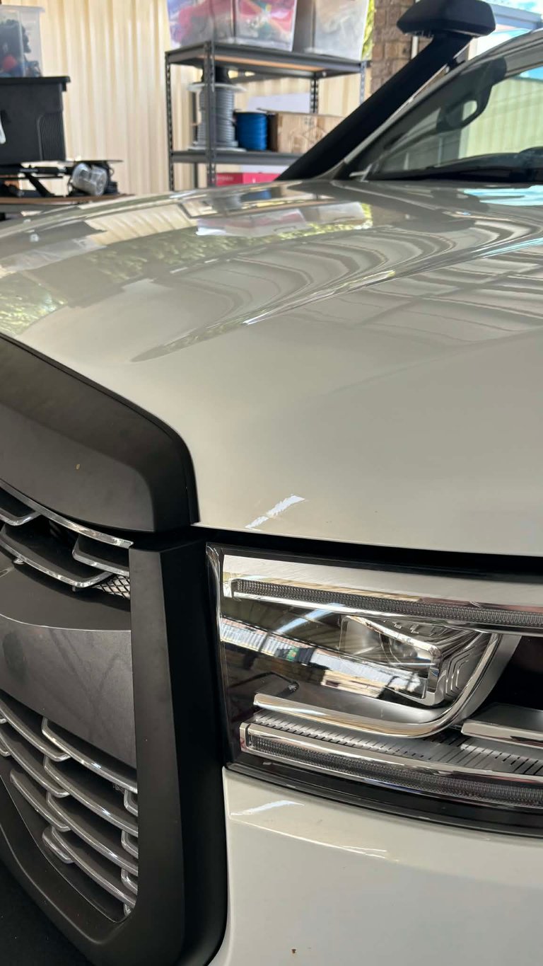 Close-up of a white 4x4 vehicle's bonnet repair using paintless dent removal.