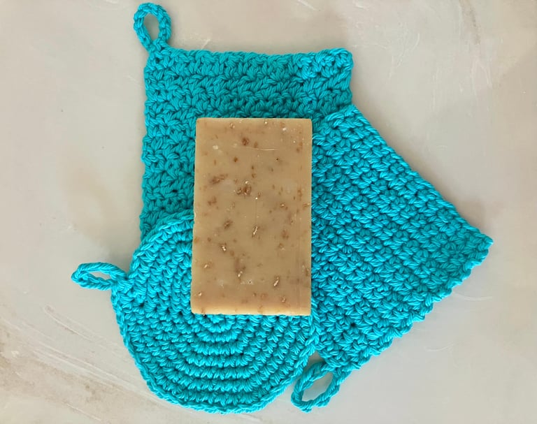 3 aqua crocheted face scrubbies with a bar of soap