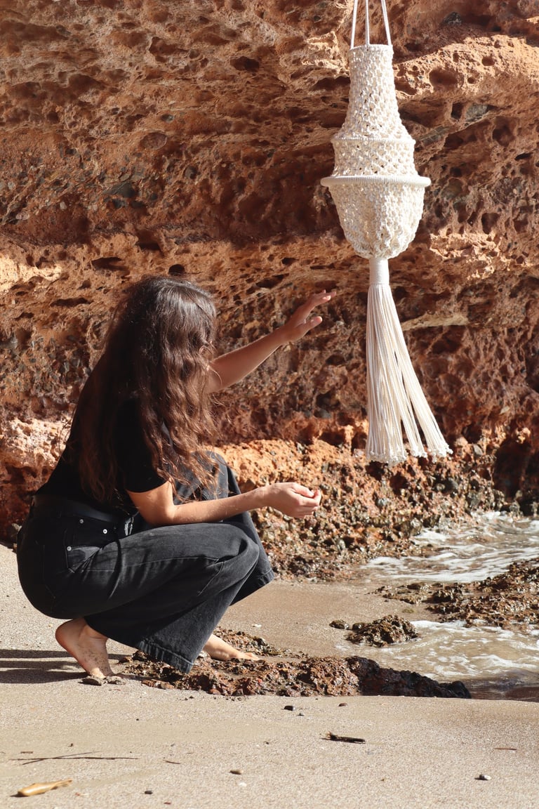 Yo, la artista textil en una playa con una piezas mía de macramé 