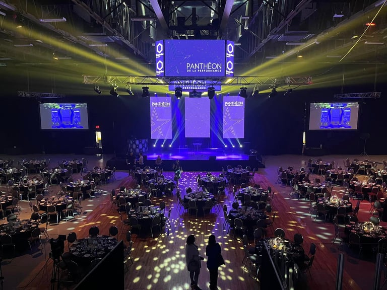 Grand gala ballroom setup for Pantheon de la Performance corporate event with stage lighting and banquet tables.