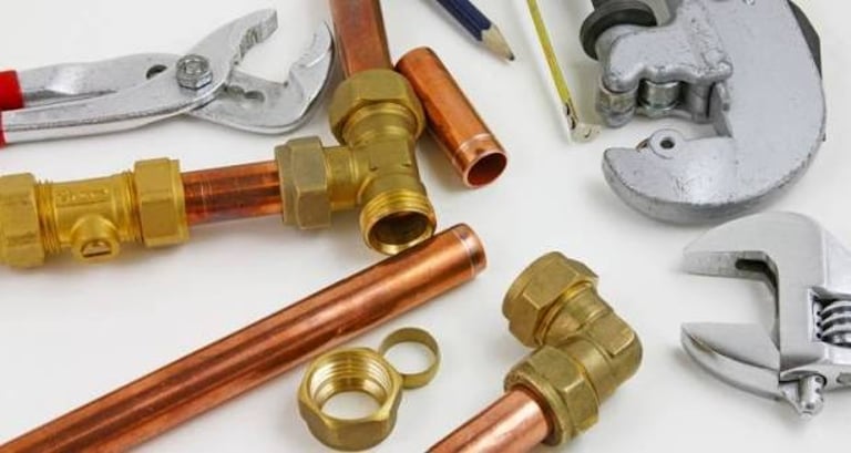 Selection of professional plumbing tools, copper pipes, and brass fittings 