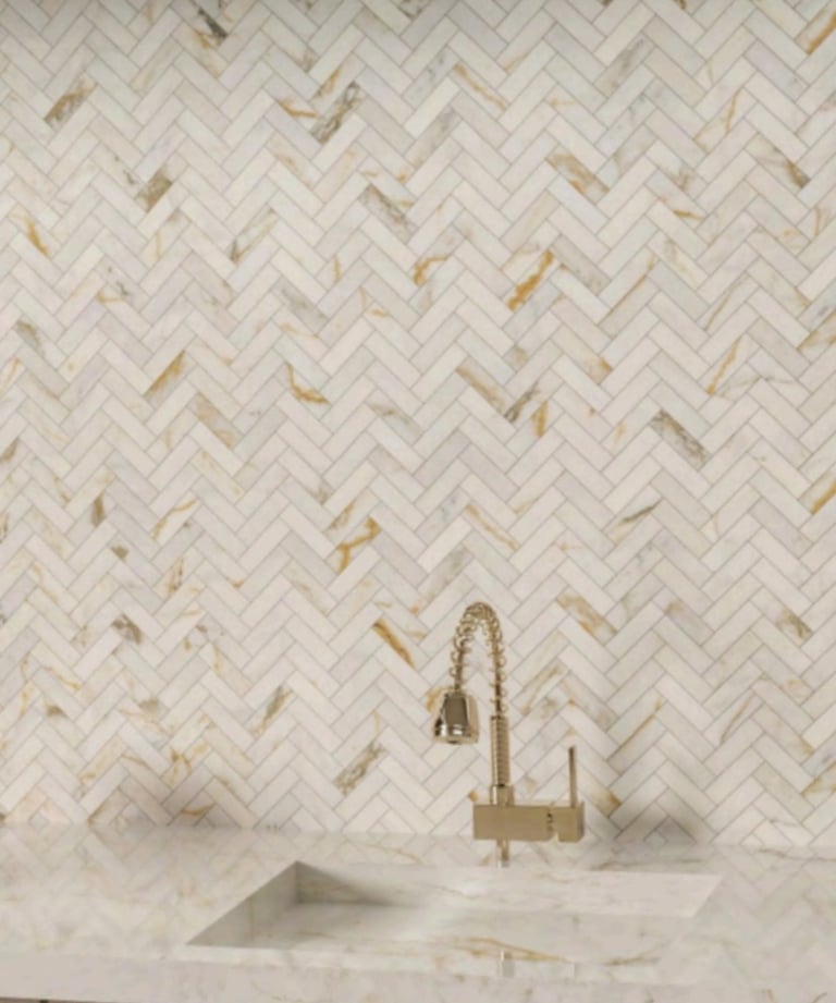 Close-up of a modern kitchen with a marble countertop and mosaic wall tiles. A sleek, bronze faucet