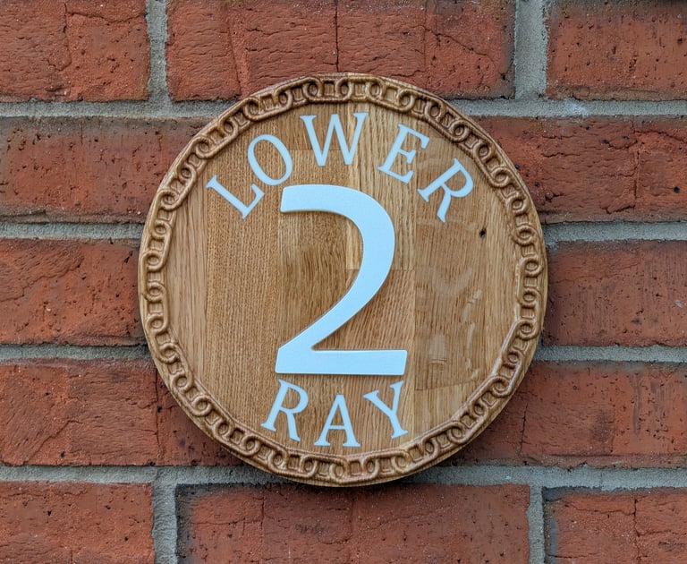 Bespoke hand-finished circular oak house sign with deep-carved 3D numerals and decorative border