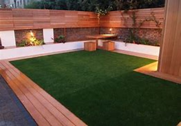 Modern backyard garden with artificial grass turf, wood panel fencing, and outdoor lighting.