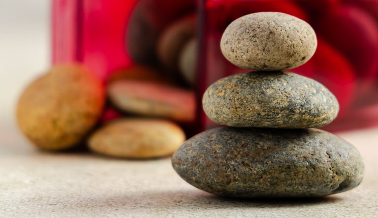 A stack of three smooth zen stones balanced on a table for meditation and wellness.