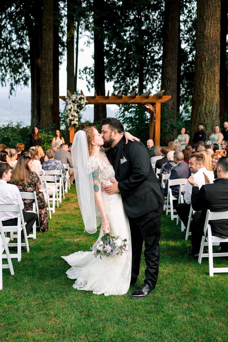 Vancouver bride and groom sharing a first kiss at an outdoor forest wedding ceremony