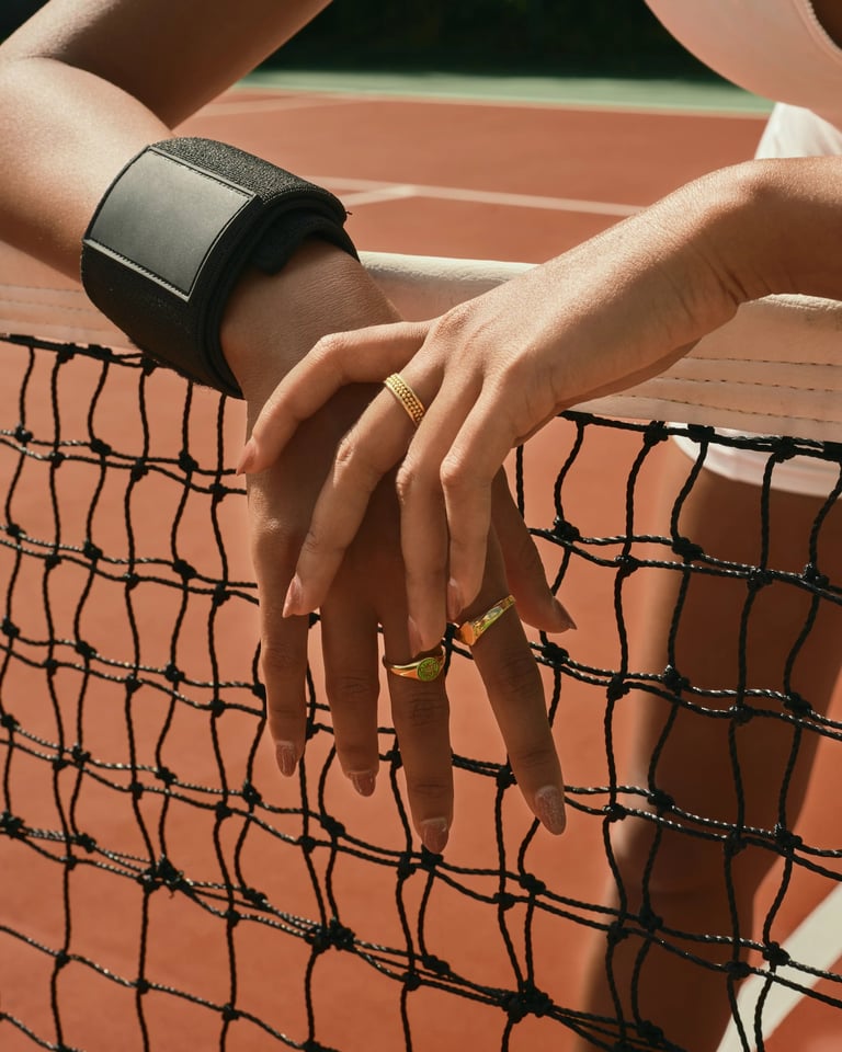 Silver rings and cuff bracelet on tennis net, luxury accessories editorial.