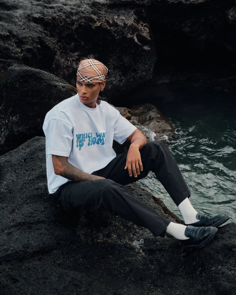 Male model in white oversized tee with brown bandana on volcanic rocks for Break the Cycle 2025.
