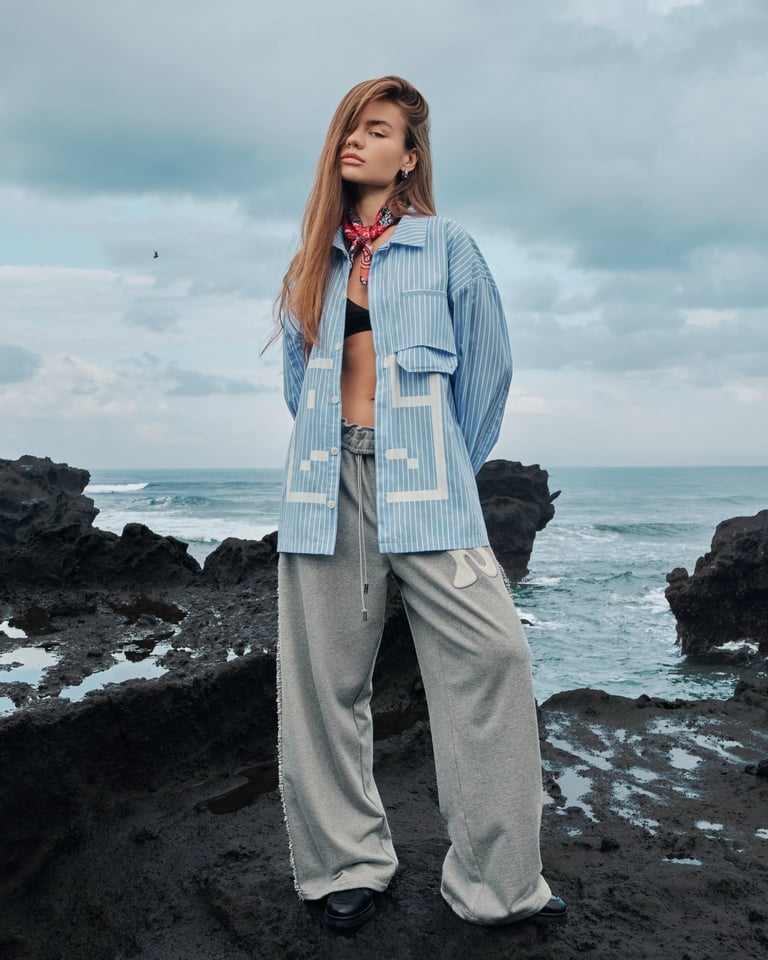 Female model in blue oversized shirt and red scarf on Bali coast for Break the Cycle Summer 2025.