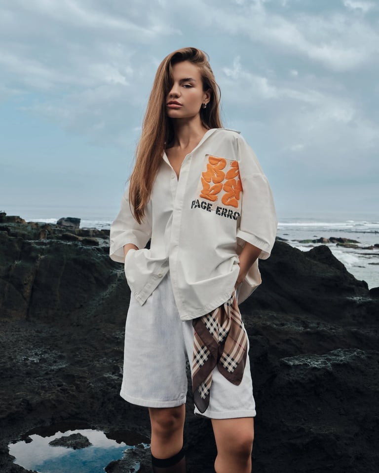 Female model in white oversized shirt on volcanic rocks for Break the Cycle Summer 2025 Bali.