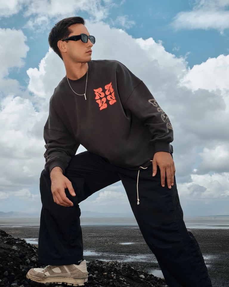 Male model in streetwear sweater posing powerfully on black rock for Break the Cycle summer campaign Bali 2025.