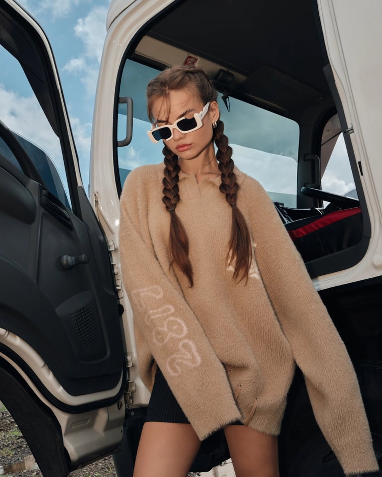 Female model in brown sweater and mini skirt standing beside truck door for Break the Cycle summer campaign Bali 2025.