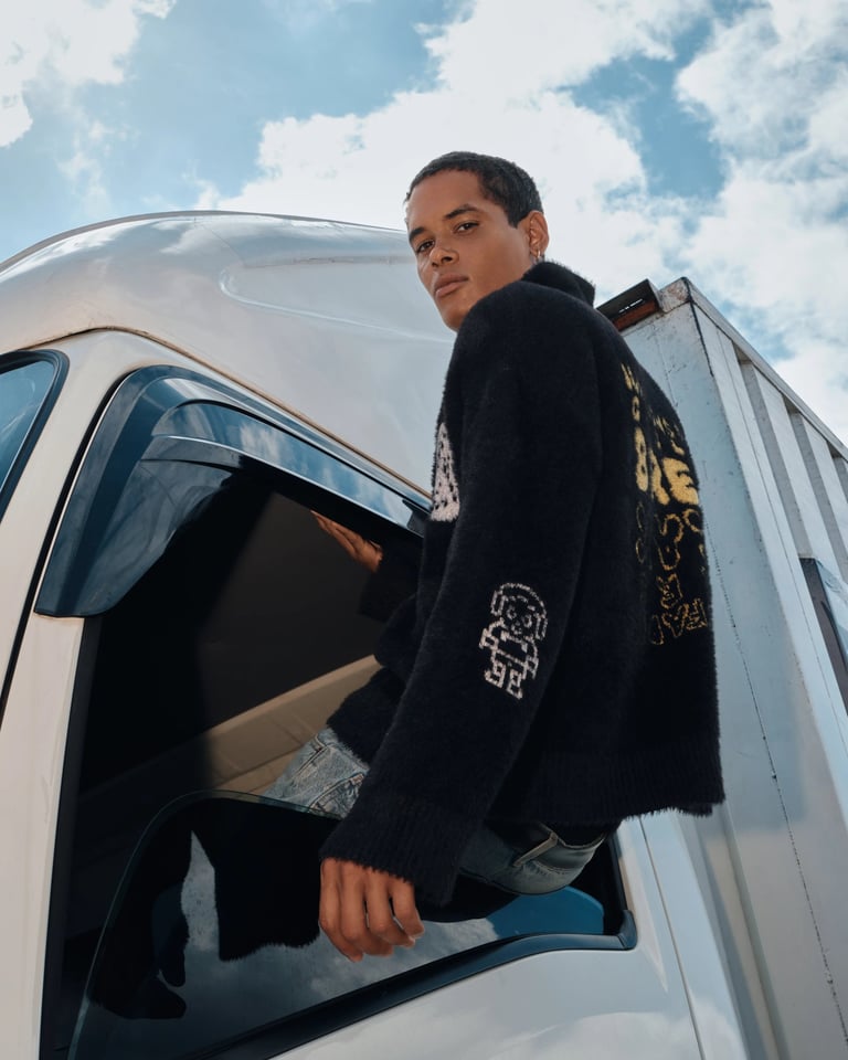 Male model in black sweater sitting on top of truck door for Break the Cycle summer campaign Bali 2025.