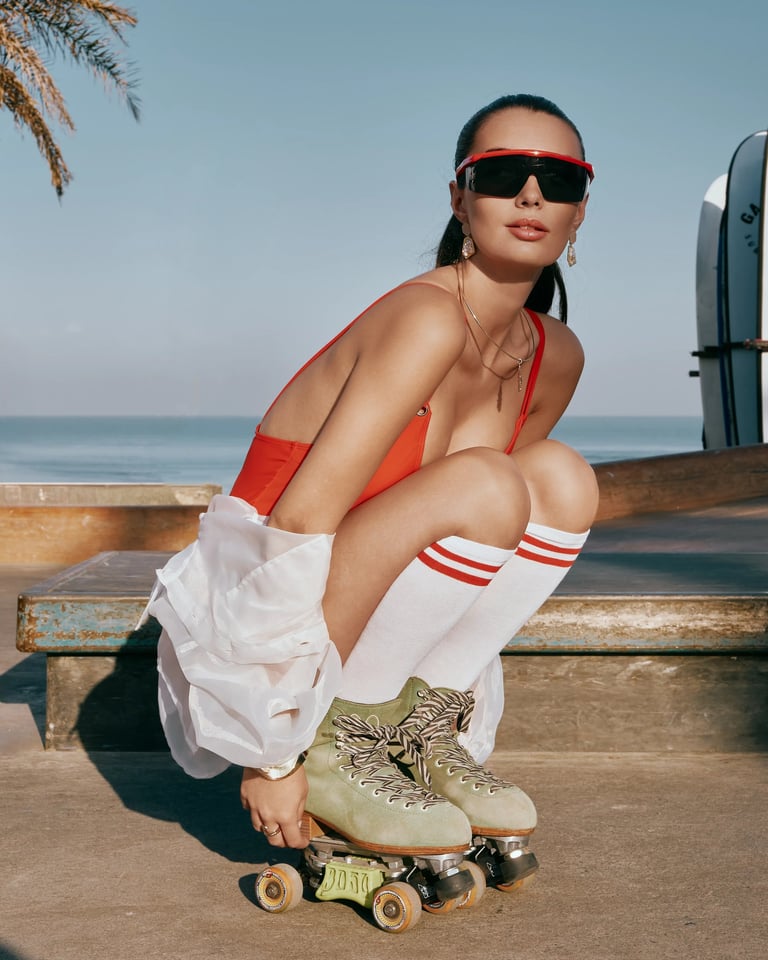Model in red swimwear and white organza outer crouching at Bali skatepark for KINI Produksi editorial.